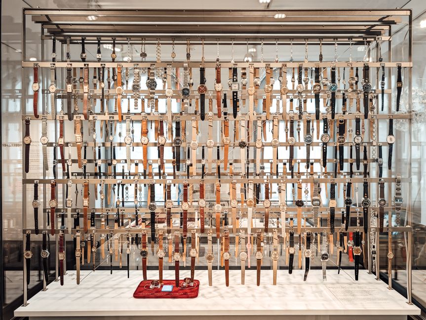 Large collection of vintage wristwatches displayed in glass case at Glashütte museum.